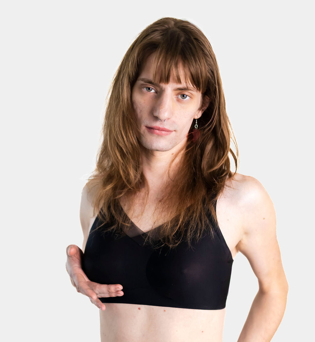Person wearing a black bra and colorful underwear on a white background