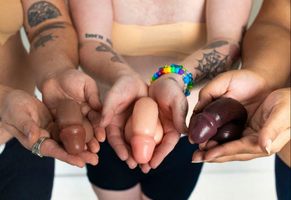 Hands of various skin tones holding silicone ftm packer against a white background