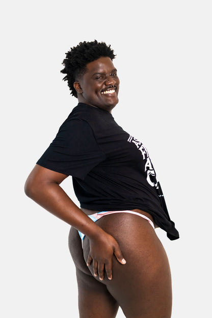 Trans person wearing a black t-shirt with text and a tucking gaff on a white background